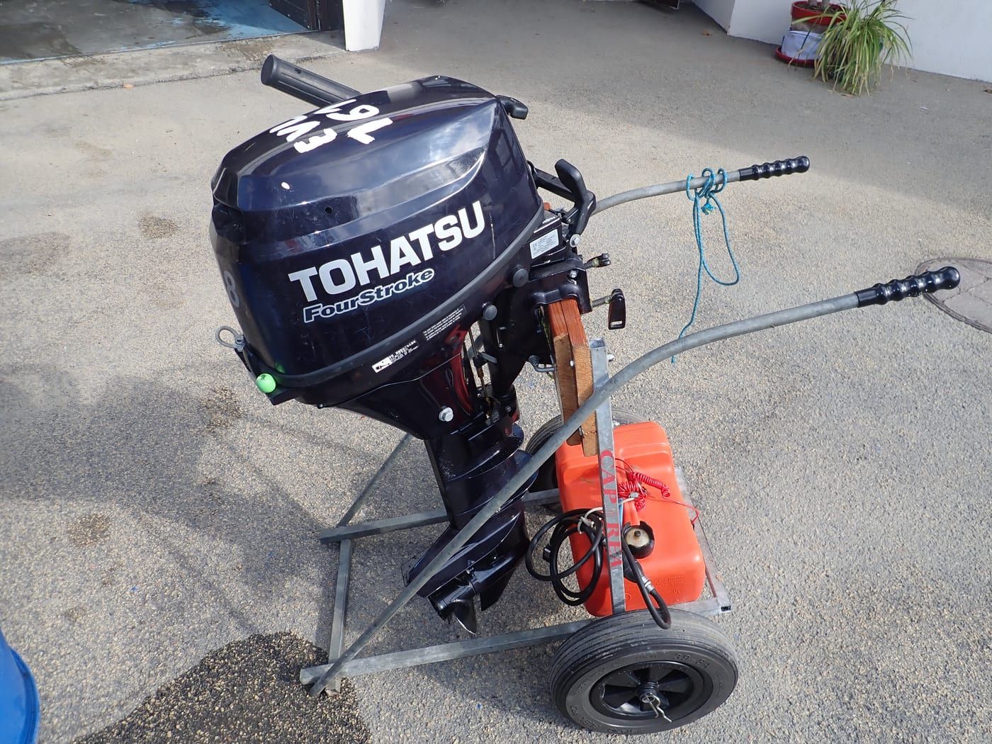 An outboard motor clamped to a wheeled stand in the shop